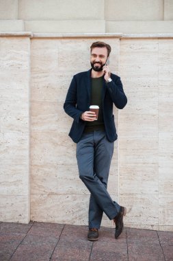 Tam boy kahve fincanı tutarak gülümseyen bir adam portresi