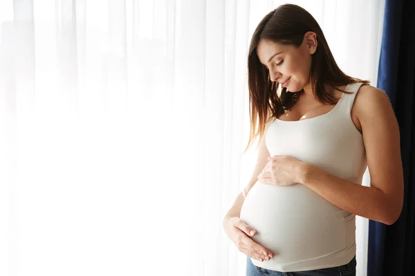 Portret van een gelukkig zwangere vrouw haar buik aan te raken — Stockfoto