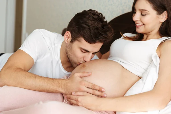 Улыбающаяся молодая беременная жена лежит в постели — стоковое фото