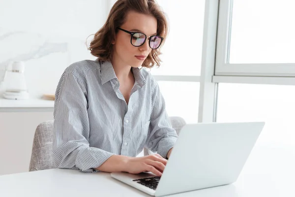 Portret van elegante jongedame texting e-mail op laptop terwijl si — Stockfoto