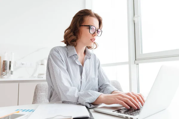 Jovem mulher séria em camisa listrada digitando e-mail para seu chefe wh — Fotografia de Stock