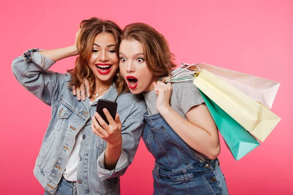 Sorprendió a dos amigas sosteniendo bolsas de compras usando teléfono móvil . — Foto de Stock