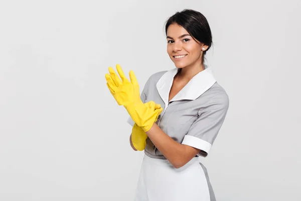 Close-up foto de jovem sorridente morena empregada doméstica em uniforme colocando — Fotografia de Stock