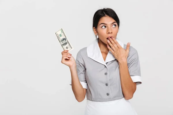 Portrait of amazed attractive maid in uniform holding hundred do — Stock Photo, Image