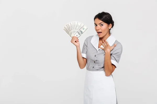 Portrait of amazed young housekeeper in uniform holding fan of d — Stock Photo, Image