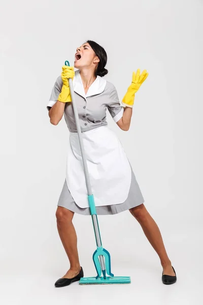 Retrato de comprimento total de empregada engraçada em uniforme cantando em — Fotografia de Stock