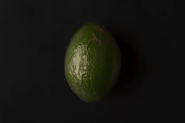 Üzerinde siyah izole olgun avokado — Stok fotoğraf