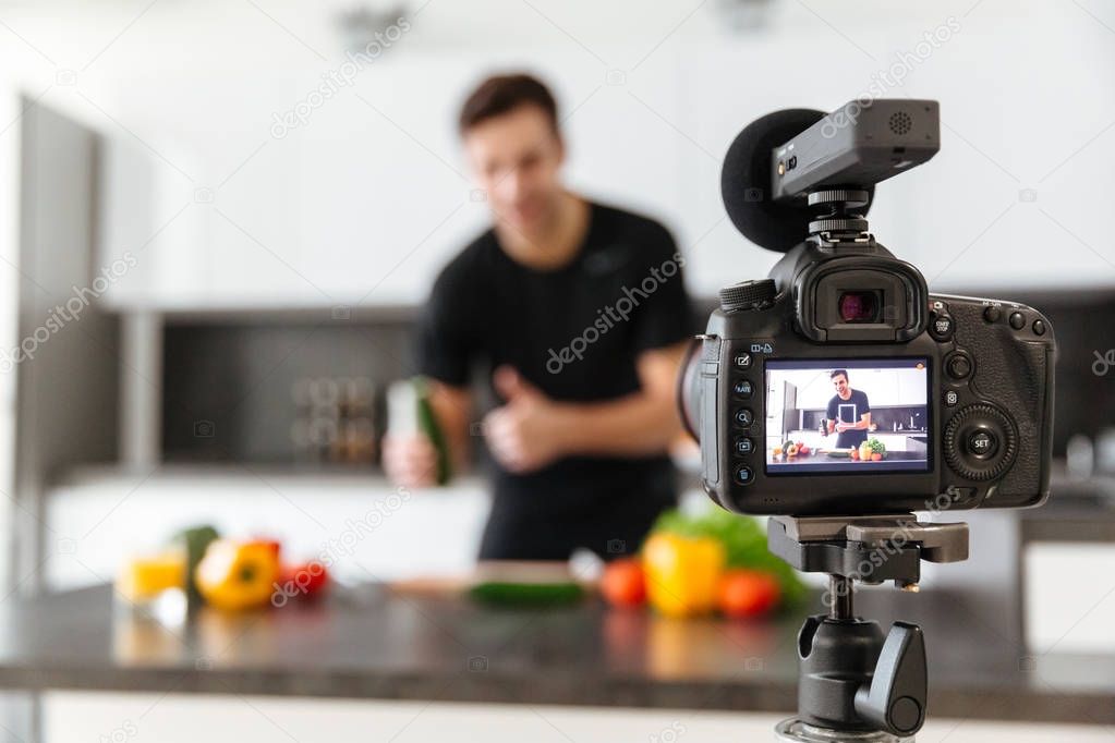 Close up of a video camera filming young smiling male blogger