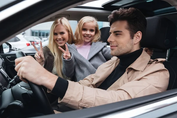 Glad ung familj som sitter i bilen visar fred gest — Stockfoto