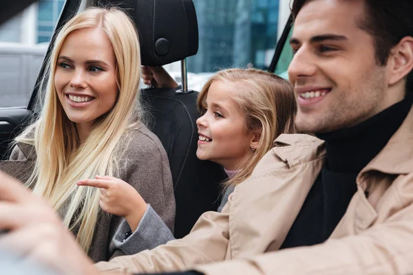 Χαμογελώντας νεαρή οικογένεια κάθεται στο αυτοκίνητο — Φωτογραφία Αρχείου