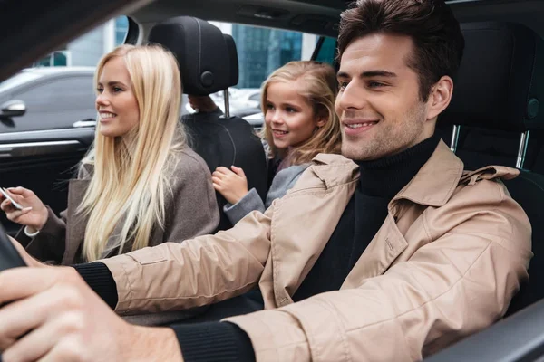 Sonriente joven familia sentada en el coche — Foto de Stock