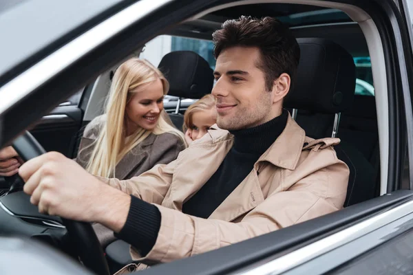 Sorridente giovane famiglia seduta in auto — Foto Stock