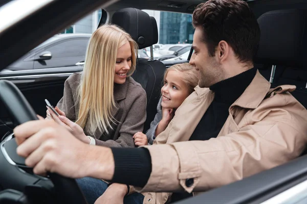 Cheerful man sitting in car with his wife and daughter — Stock Photo, Image