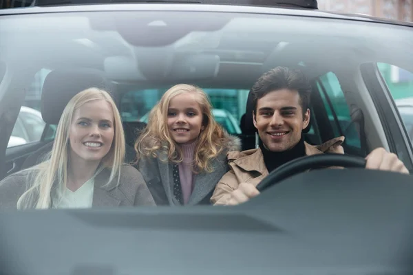 Vrolijke man zit in de auto met zijn vrouw en dochter — Stockfoto