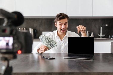 Mutfak masada oturan ve makyaj uygulayarak yeni kozmetik ürünler hakkında onun video blog bölüm filme mutlu genç adam