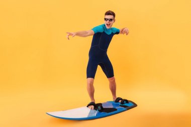 Wetsuit ve sörf tahtası kullanarak güneş gözlüğü mutlu sörfçü görüntüsünü