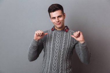 Smiling brunette man in sweater indicates itself clipart