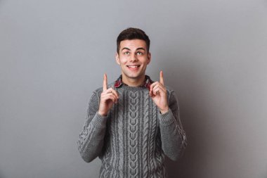 İşaret ve ararken kazaklı şaşırmış mutlu esmer adam
