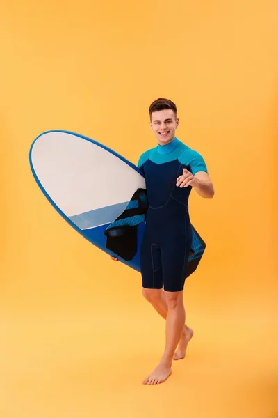 サーフボードを抱えて歩いて笑顔のサーファーの全身画像 — ストック写真
