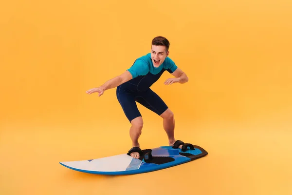 Imagen de un surfista feliz en traje de neopreno usando tabla de surf —  Fotos de Stock