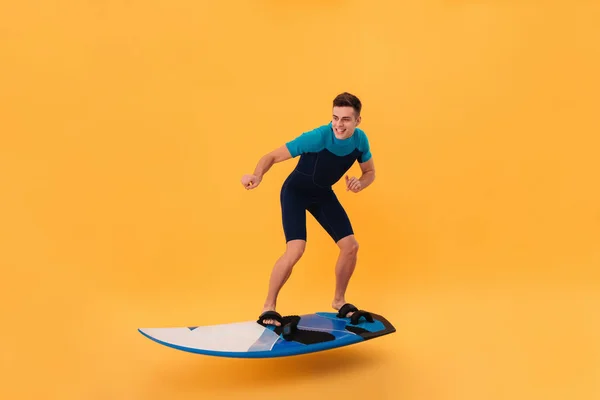 Изображение улыбающегося серфера в гидрокостюме с помощью доски для сёрфинга — стоковое фото
