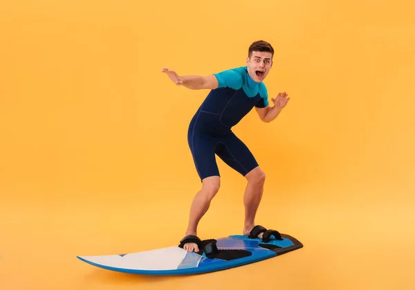 Imagem do surfista assustado em fato de mergulho usando prancha de surf — Fotografia de Stock