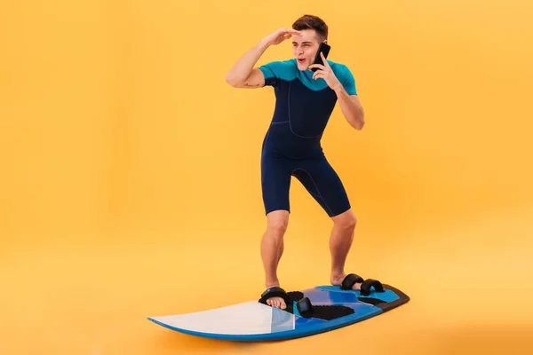 Foto van Happy surfer in wetsuit met behulp van surfplank — Stockfoto