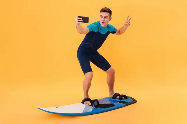 Bild eines glücklichen Surfers im Neoprenanzug mit Surfbrett — Stockfoto