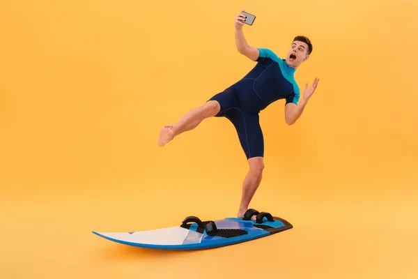 Foto de Surfista juguetón en traje de neopreno usando tabla de surf — Foto de Stock