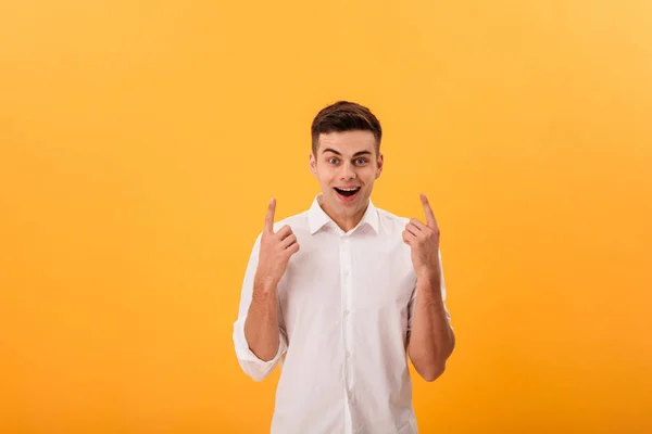 Surprised happy man in white shirt pointing up — Stock Photo, Image