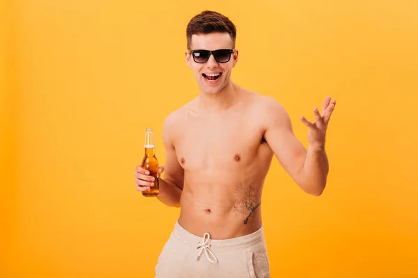Hombre desnudo alegre en pantalones cortos y gafas de sol sosteniendo cerveza — Foto de Stock
