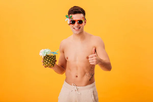 Hombre desnudo sonriente en pantalones cortos y gafas de sol inusuales celebración de cóctel — Foto de Stock