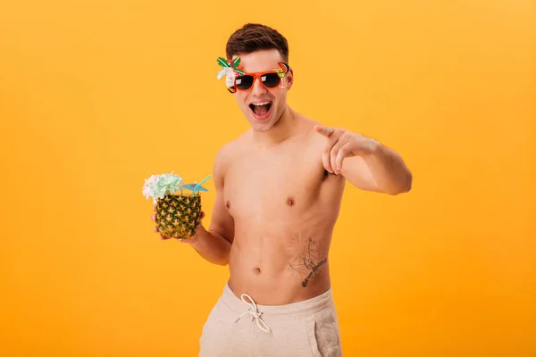 Hombre desnudo alegre en pantalones cortos y gafas de sol inusuales celebración de cóctel — Foto de Stock