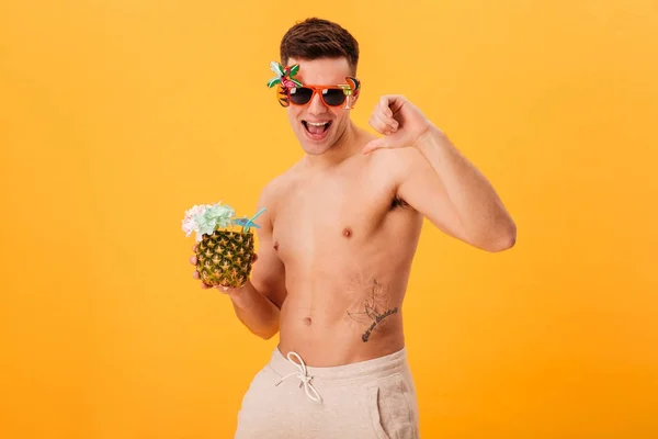 Feliz hombre desnudo en pantalones cortos y gafas de sol inusual celebración de cóctel — Foto de Stock