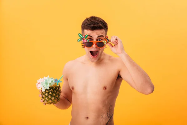 Hombre desnudo sorprendido en pantalones cortos y gafas de sol inusuales celebración de cóctel — Foto de Stock