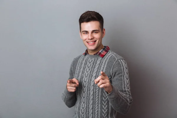 Sorridente uomo bruna in maglione che punta e guarda la fotocamera — Foto Stock