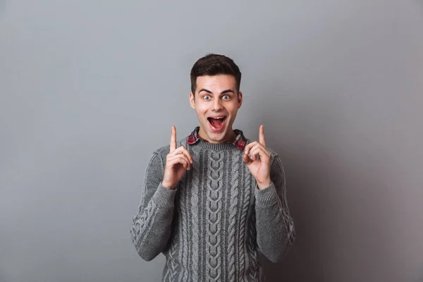 Sorprendido morena feliz hombre en suéter apuntando hacia arriba —  Fotos de Stock