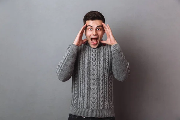 Σοκαρισμένος ευτυχισμένος άνθρωπος μελαχρινή σε πουλόβερ κρατώντας το κεφάλι του — Φωτογραφία Αρχείου