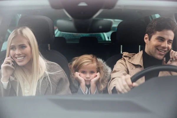 Sorglig liten flicka sitter i bilen medan hennes föräldrar talar — Stockfoto
