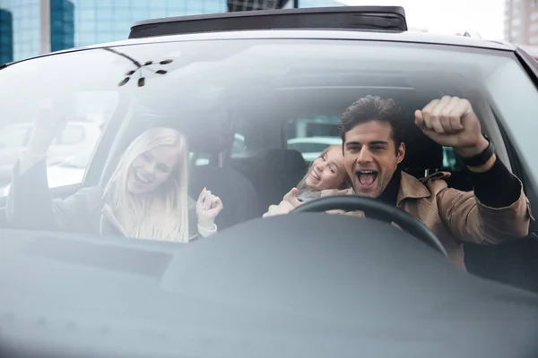 Felice uomo emotivo seduto in auto con moglie e figlia — Foto Stock