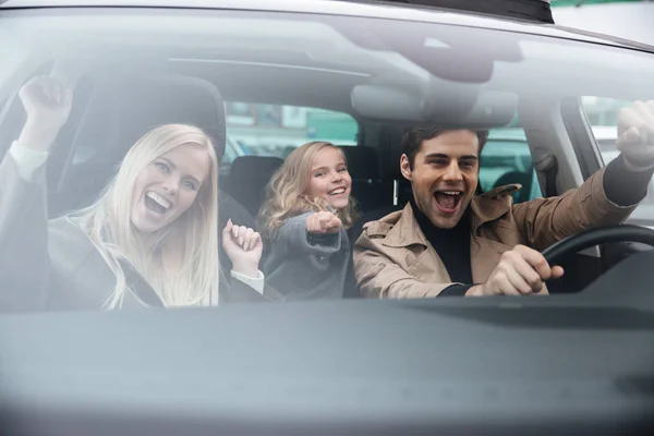 Happy emotional man sitting in car with wife and daughter — Stock Photo, Image