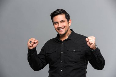 Mutlu genç yakışıklı adam kazanan jest gösterilen.