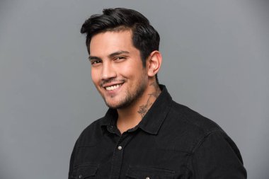 Üzerinde gri izole ayakta neşeli yakışıklı genç