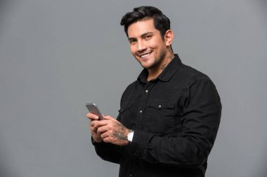 Gülümseyen genç yakışıklı adam cep telefonuyla sohbet.