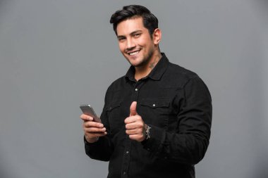 Genç adam cep telefonuyla sohbet yukarı başparmak gösterilen gülümseyen.