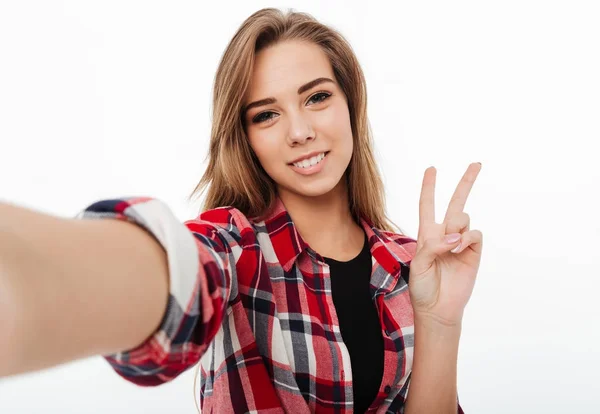 Retrato de uma menina encantadora feliz em camisa xadrez tirando uma selfie — Fotografia de Stock