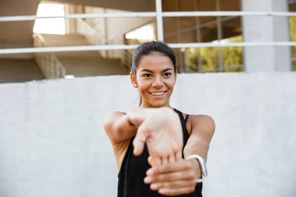 Retrato de una chica de fitness sonriente estirando las manos —  Fotos de Stock