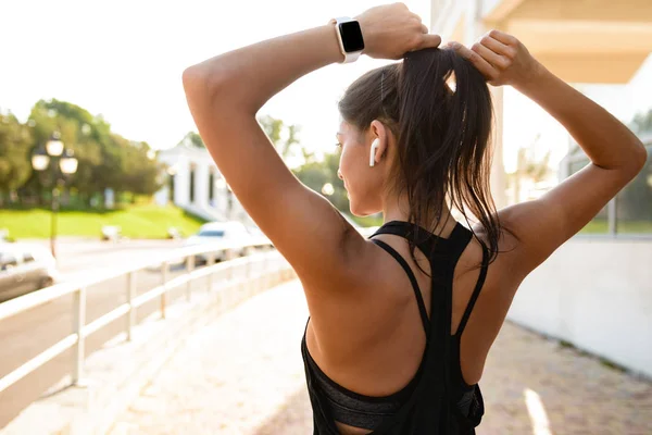 Vista trasera de una joven chica fitness en auriculares — Foto de Stock