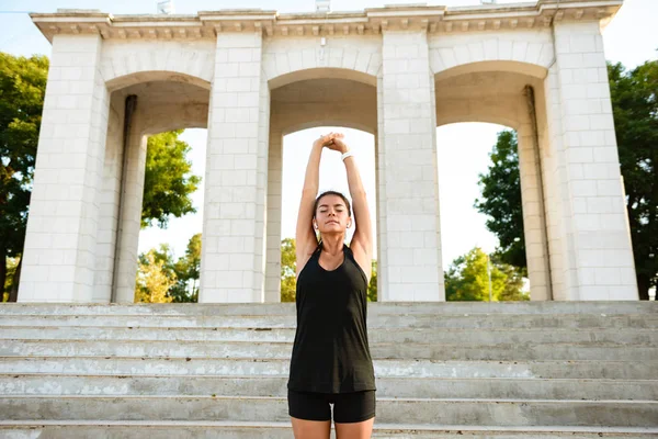 Porträtt av en leende fitness flicka stretching hennes händer — Stockfoto