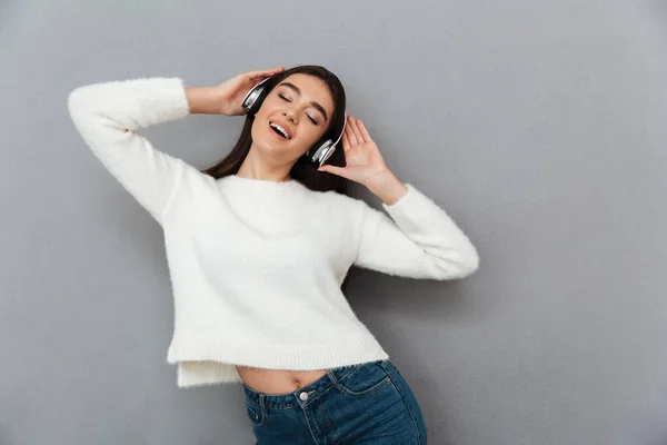 Mujer morena alegre en suéter y auriculares escuchando musi —  Fotos de Stock